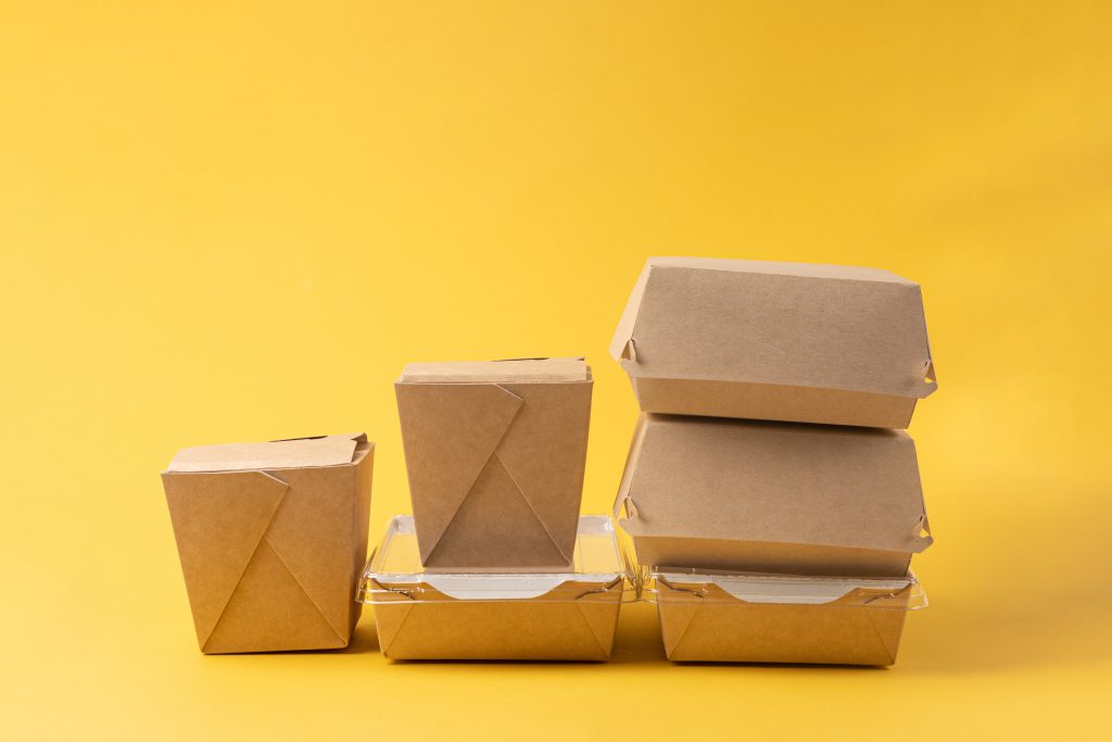 Disposable food delivery boxes on yellow background